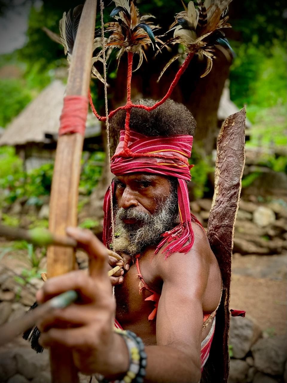 An Alor village elder in feathered ceremonial headdress and traditional ikat