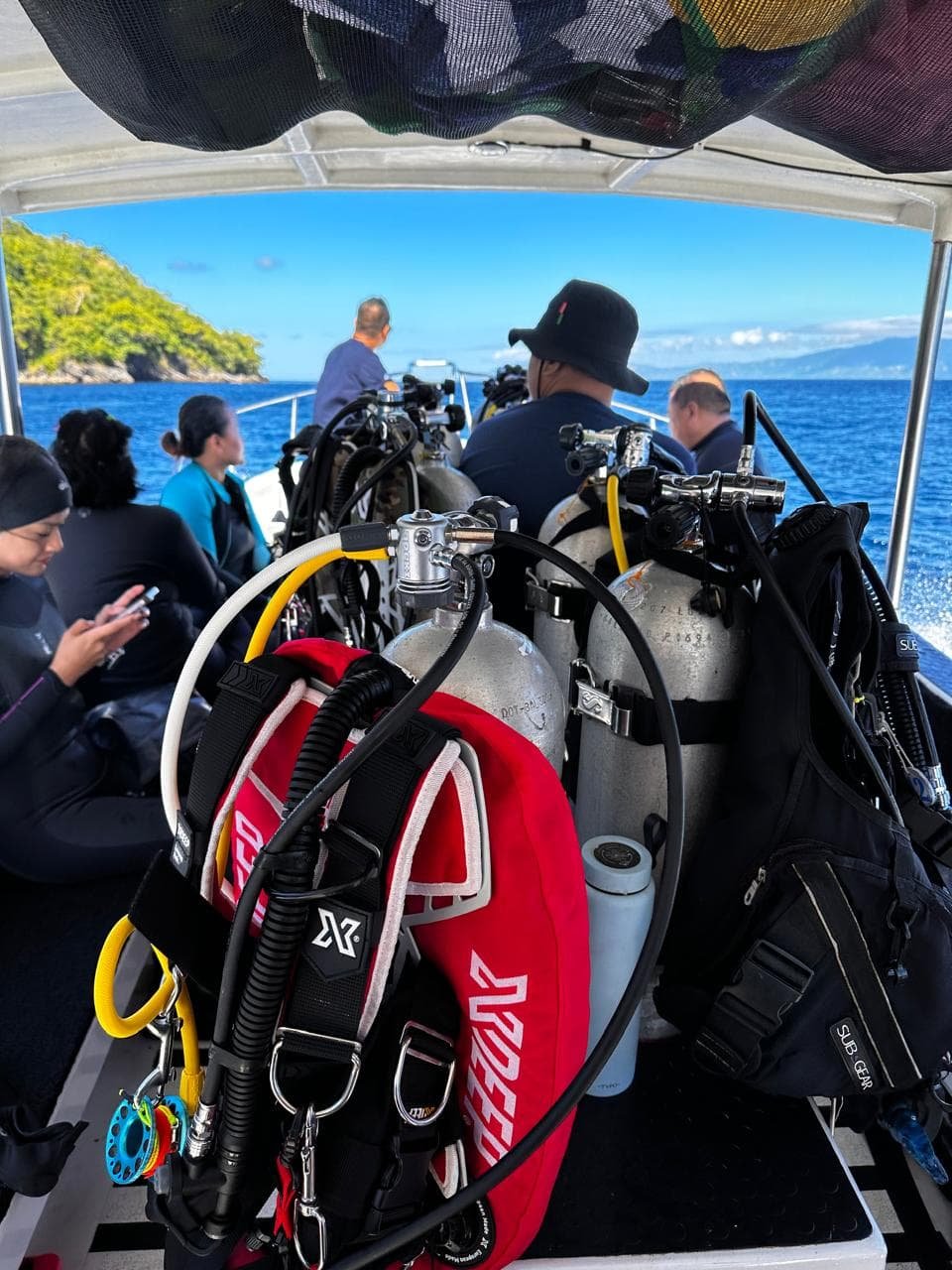 Dive boat loaded with tanks and BCDs, mountains of Pantar in the distance